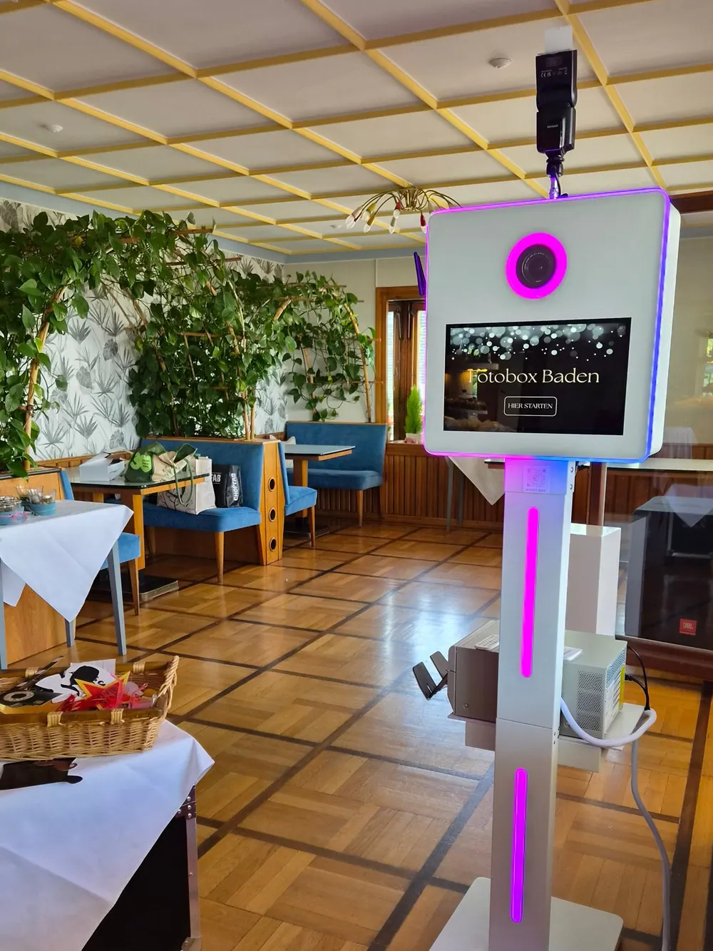 Die weiße Fotobox mit pinker LED-Beleuchtung in einem Hochzeitssaal